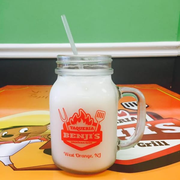 A Benji's Taqueria Mexican Grill mason jar drink with a straw on a colorful placemat.