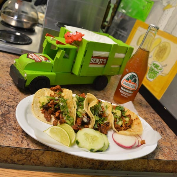 Benji's Taqueria Mexican Grill tacos with lime, cucumber, and radish, next to a Jarritos soda and toy truck.